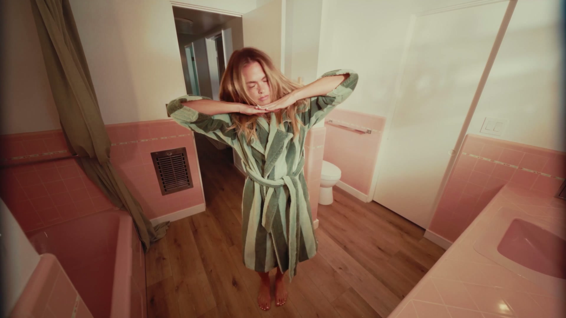 Summer Mckeen in a striped robe in a pink-tiled bathroom, from GRWM